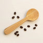 Bubble Gallery bamboo coffee scoop with integrated bag clip, shown with scattered roasted coffee beans.