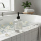Bubble Gallery clear glass liquid soap dispenser with crystalline pattern and black pump, shown in a bathroom setting.
