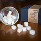 Bubble Gallery Cheeky Bits cloth wipe solution cubes in a glass jar next to a stack of navy blue reusable cloth wipes.