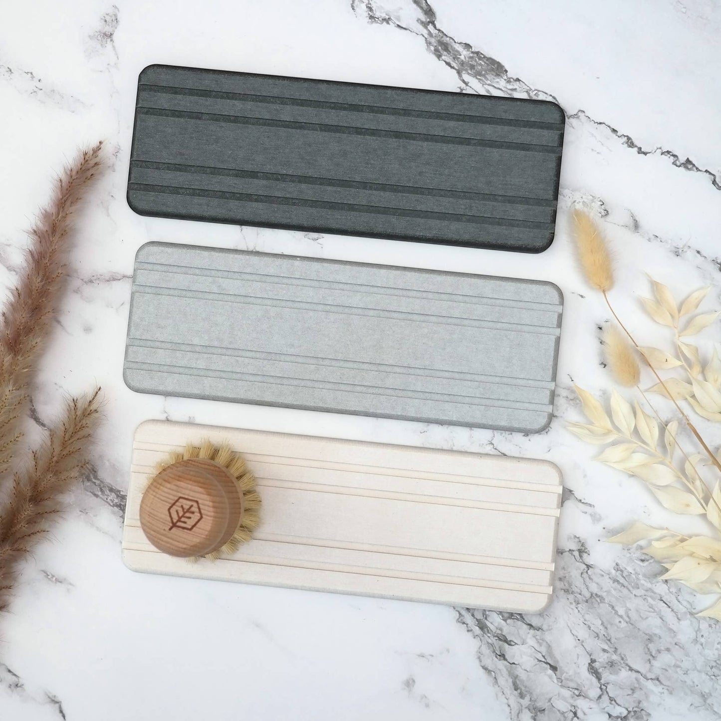 Bubble Gallery diatomaceous earth bottle tray in charcoal, light grey, and natural beige. Features subtle channels for airflow and a wooden dish brush.