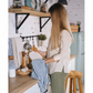 Bubble Gallery emerald green textured glass soap dispenser on a kitchen counter with a woman drying a plate nearby