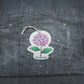 Bubble Gallery hydrangea pop-up sponge with a floral design and hanging string on a dark textured background