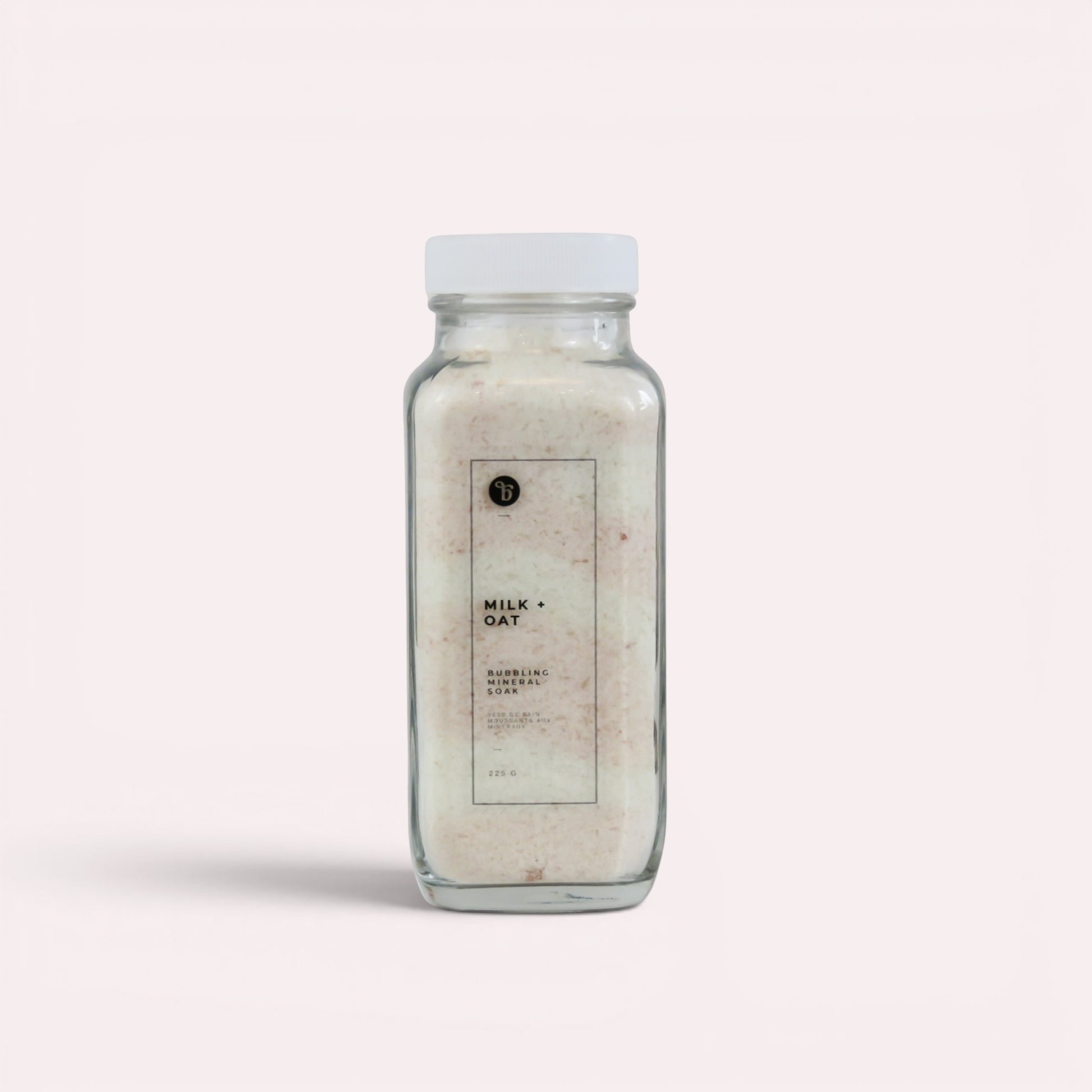 Bubble Gallery Milk + Oat Bubbling Magnesium Bath Soak in a glass jar with a white lid. Relaxing bath salts.