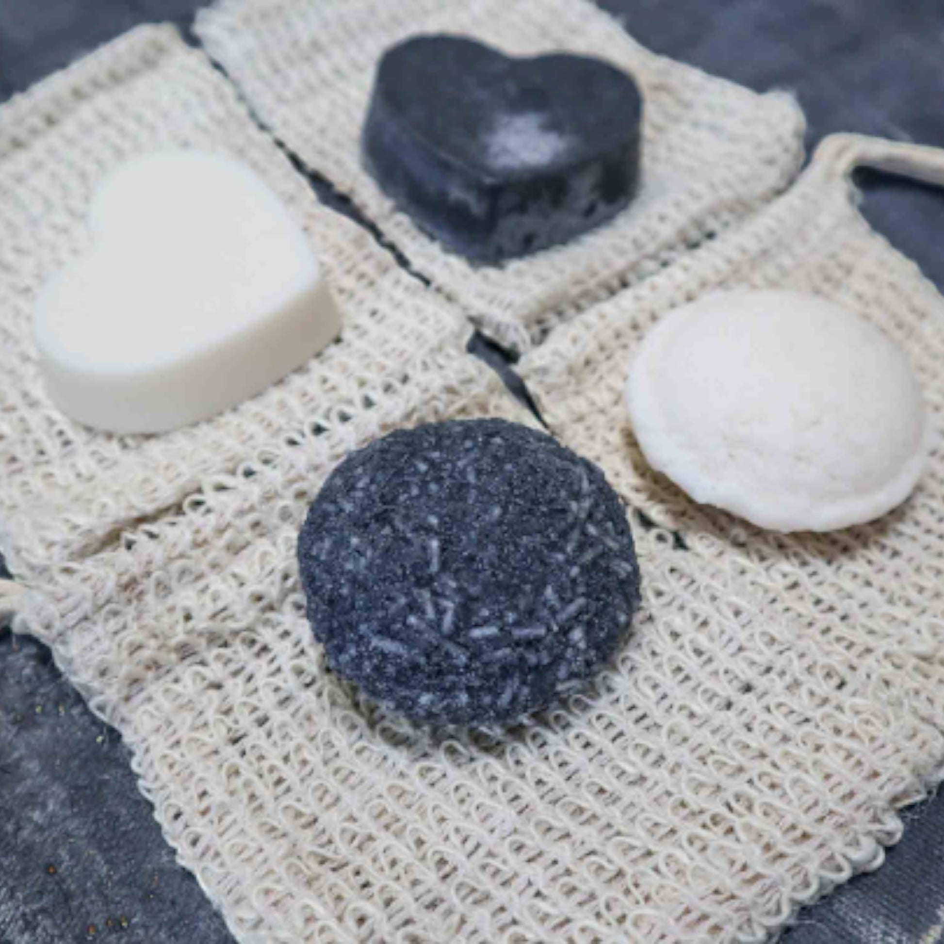 Bubble Gallery rebalancing shampoo and conditioner bars in round and heart shapes with natural sisal soap saver bags.