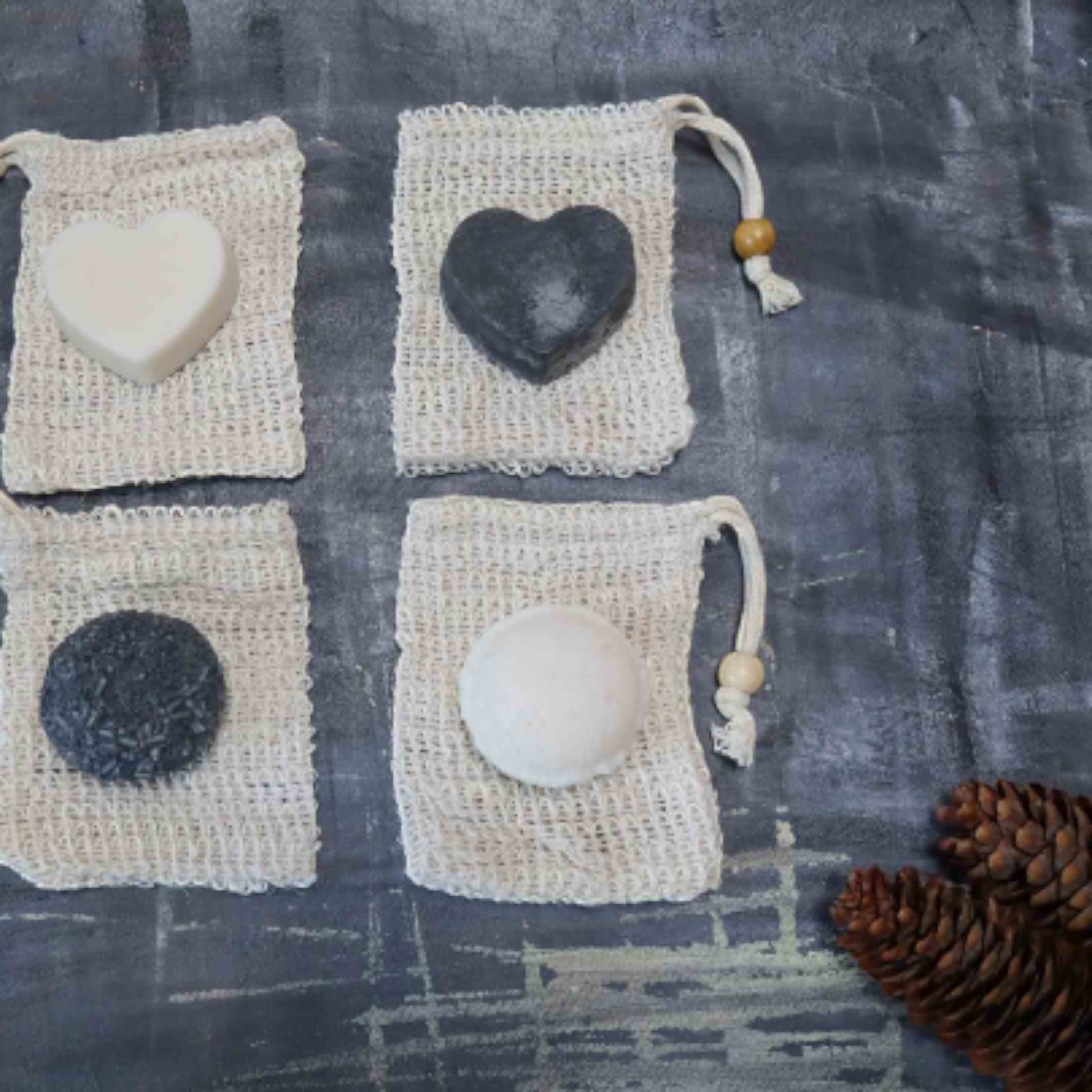 Bubble Gallery rebalancing shampoo and conditioner bars in individual mesh drawstring bags on a dark textured surface.