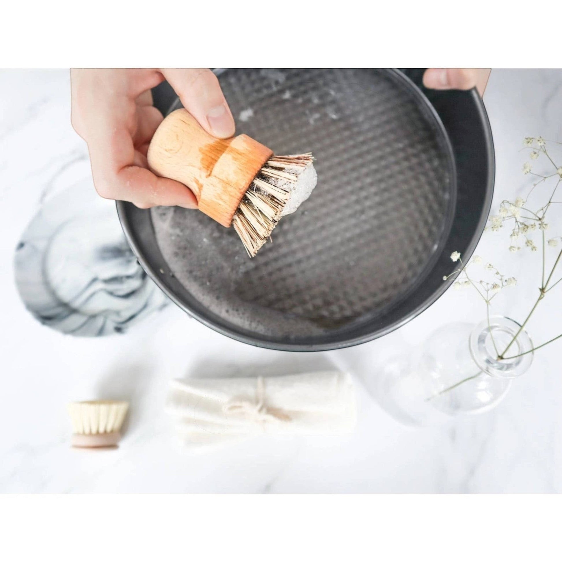 Bubble Gallery sustainable sisal and palm pot scrubber cleaning a dark metal pan with soapy water